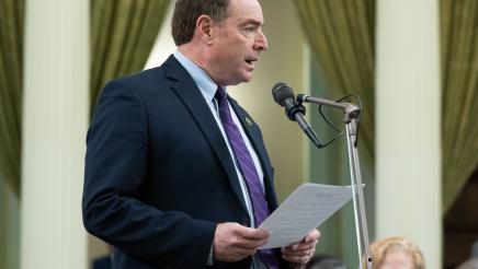 Asm. Connolly at microphone, holding papers and speaking